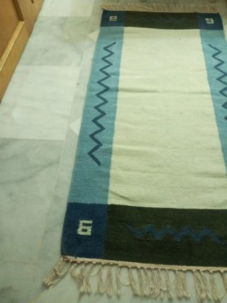 Alfombra lana crema y azul con cenefa.
