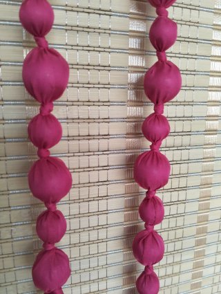 Collar largo de tela y bolas de madera en fucsia.