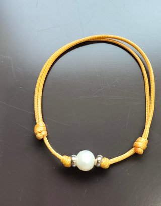 Pulsera cordón con perla blanca y detalles platead