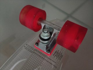 Monopatín transparente con ruedas rojas