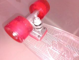 Monopatín transparente con ruedas rojas