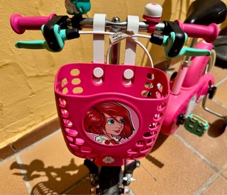 Bicicleta infantil rosa con casco y ruedines