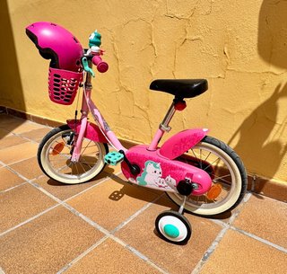 Bicicleta infantil rosa con casco y ruedines