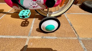 Bicicleta infantil rosa con casco y ruedines