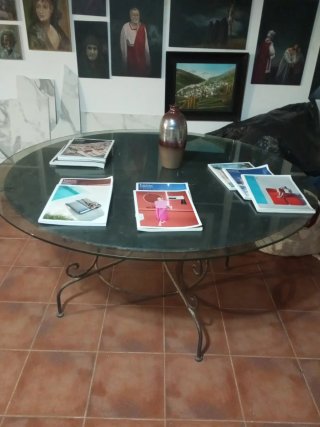 Mesa redonda con patas y base de hierro y cristal.