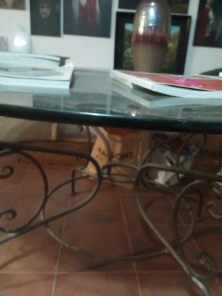 Mesa redonda con patas y base de hierro y cristal.