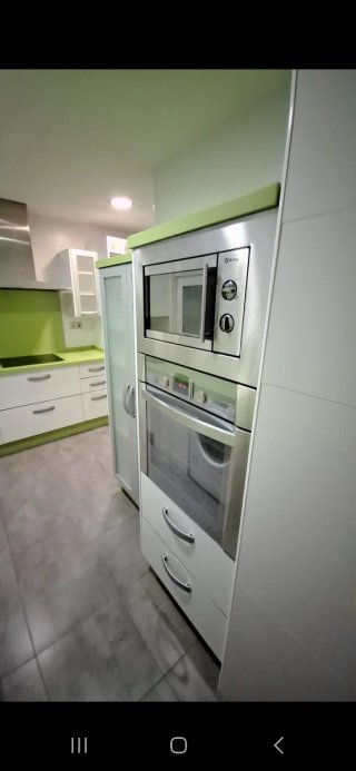 Cocina con muebles y encimera de cocina verde pie