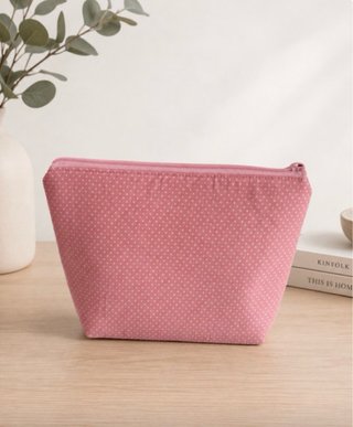Neceser triangular rosa con topitos blancos.