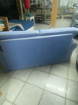 Sofá Cama en tela azul con ribetes blancos.