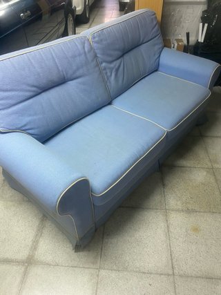 Sofá Cama en tela azul con ribetes blancos.