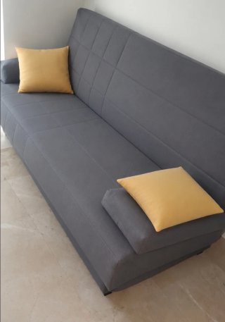 Sofá cama gris con cojines amarillos