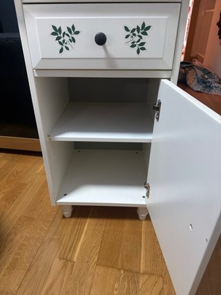 Mesita de noche blanca con hojas verdes
