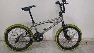 Bicicleta BMX plateada con ruedas amarillas