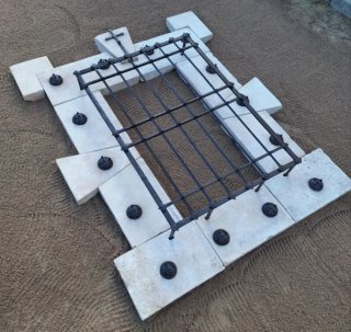 Ventana de piedra y forja con cruz