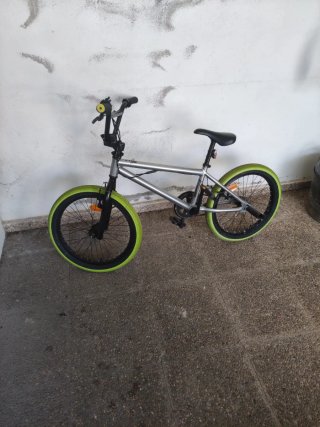 Bicicleta BMX plateada con ruedas verdes