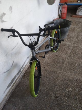 Bicicleta BMX plateada con ruedas verdes