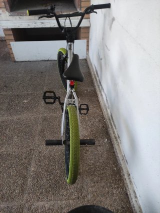 Bicicleta BMX plateada con ruedas verdes
