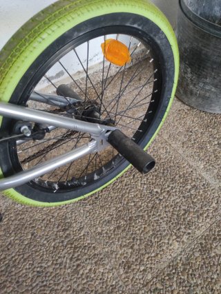 Bicicleta BMX plateada con ruedas verdes