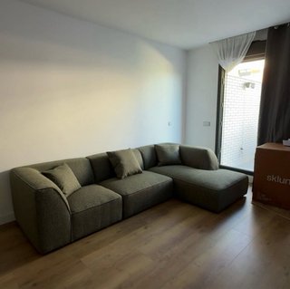 Sofá modular verde con 3 cojines.