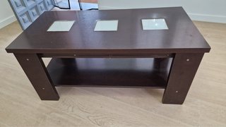 Mesa de centro oscura con estante y armario.