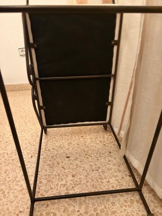 Banqueta de hierro forjado con asiento beige.