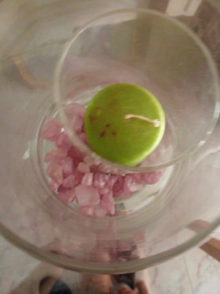 Jarrón de cristal con vela verde y piedras