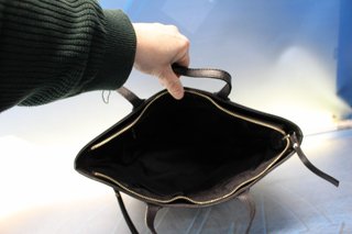 Bolso de polipiel negra tipo tote o trapezoidal, de mano.