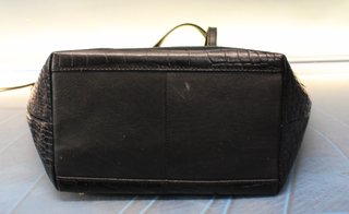 Bolso de polipiel negra tipo tote o trapezoidal, de mano.