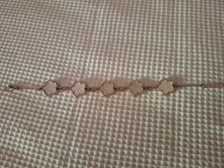Pulsera dorada con motivos florales blancos