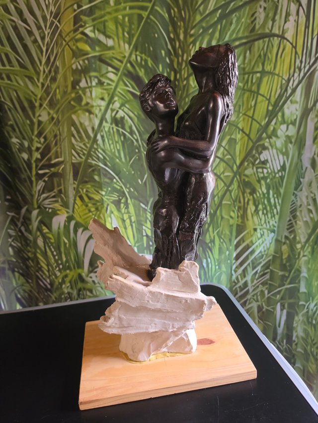 Coppia di sculture che abbracciano la base in legno