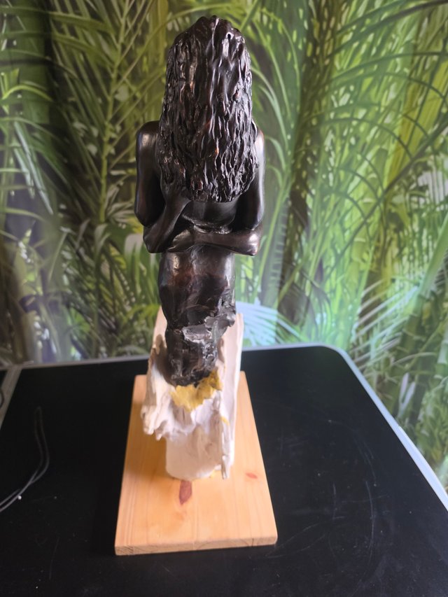 Coppia di sculture che abbracciano la base in legno