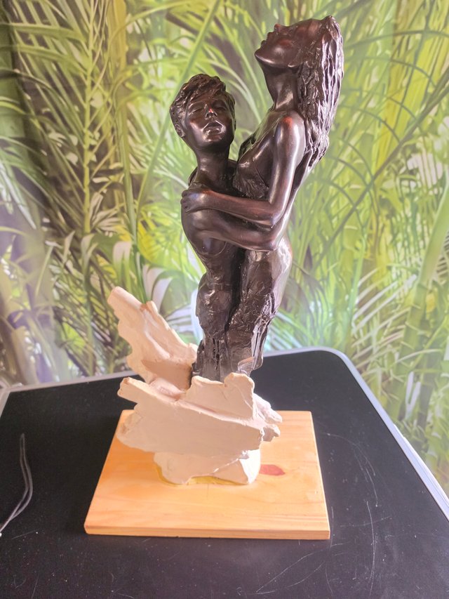 Coppia di sculture che abbracciano la base in legno