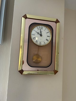 Reloj de pared con péndulo dorado