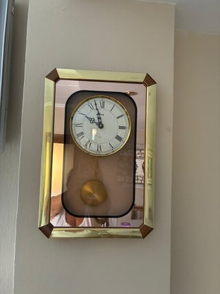 Reloj de pared con péndulo dorado