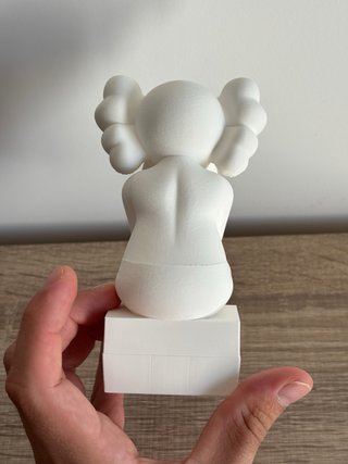Figura estilo Kaws sentado en cubo
