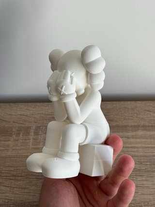Figura estilo Kaws sentado en cubo