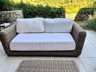 Muebles de ratán marrones con cojines blancos