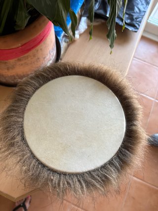 Tambor africano decorado con plumas y coco.