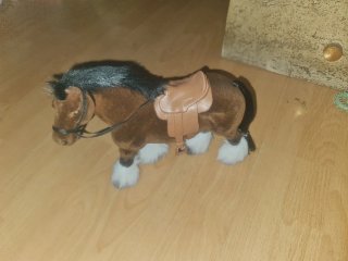 Caballo de peluche marrón con silla