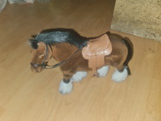 Caballo de peluche marrón con silla