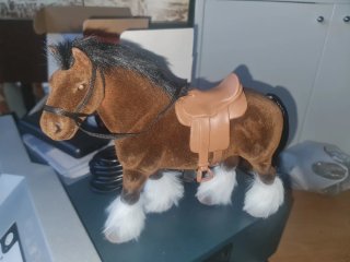 Caballo de peluche marrón con silla