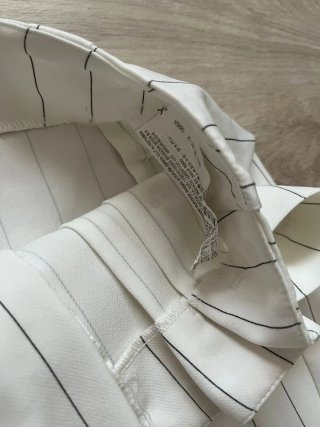 Pantalón blanco de rayas con cinturón.