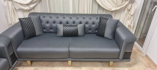Sofá y sillón gris con detalles dorados modernos.