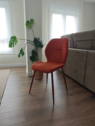 Silla tapizada con pata metálica, color terracota.