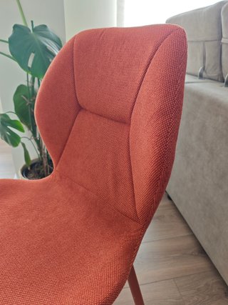 Silla tapizada con pata metálica, color terracota.