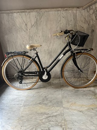 Bicicleta de paseo negra con cesta y portabultos.