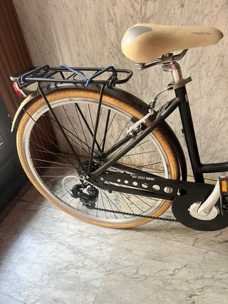 Bicicleta de paseo negra con cesta y portabultos.