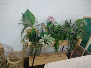 Macetero de madera con flores artificiales.