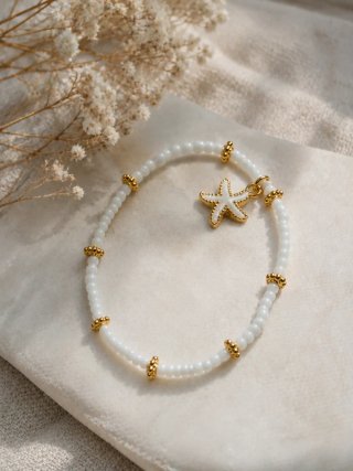 Pulsera blanca con abalorios dorados y estrella