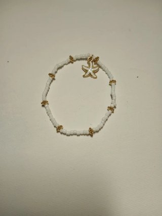 Pulsera blanca con abalorios dorados y estrella
